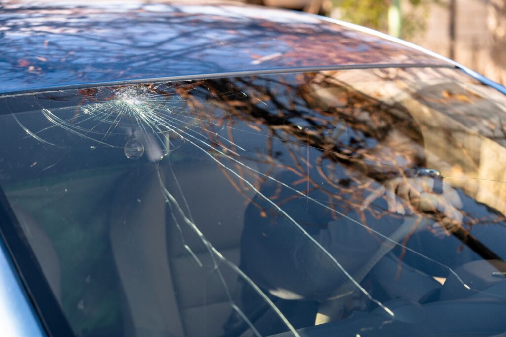 Picture of a woman sitting in a car, frustrated about her broken windshield.